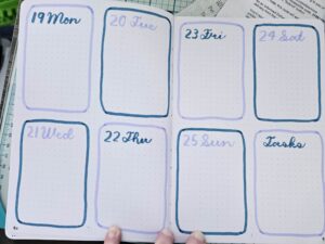Two page spread in a dotted journal with 8 rounded boxes labeled with dates and days of the week